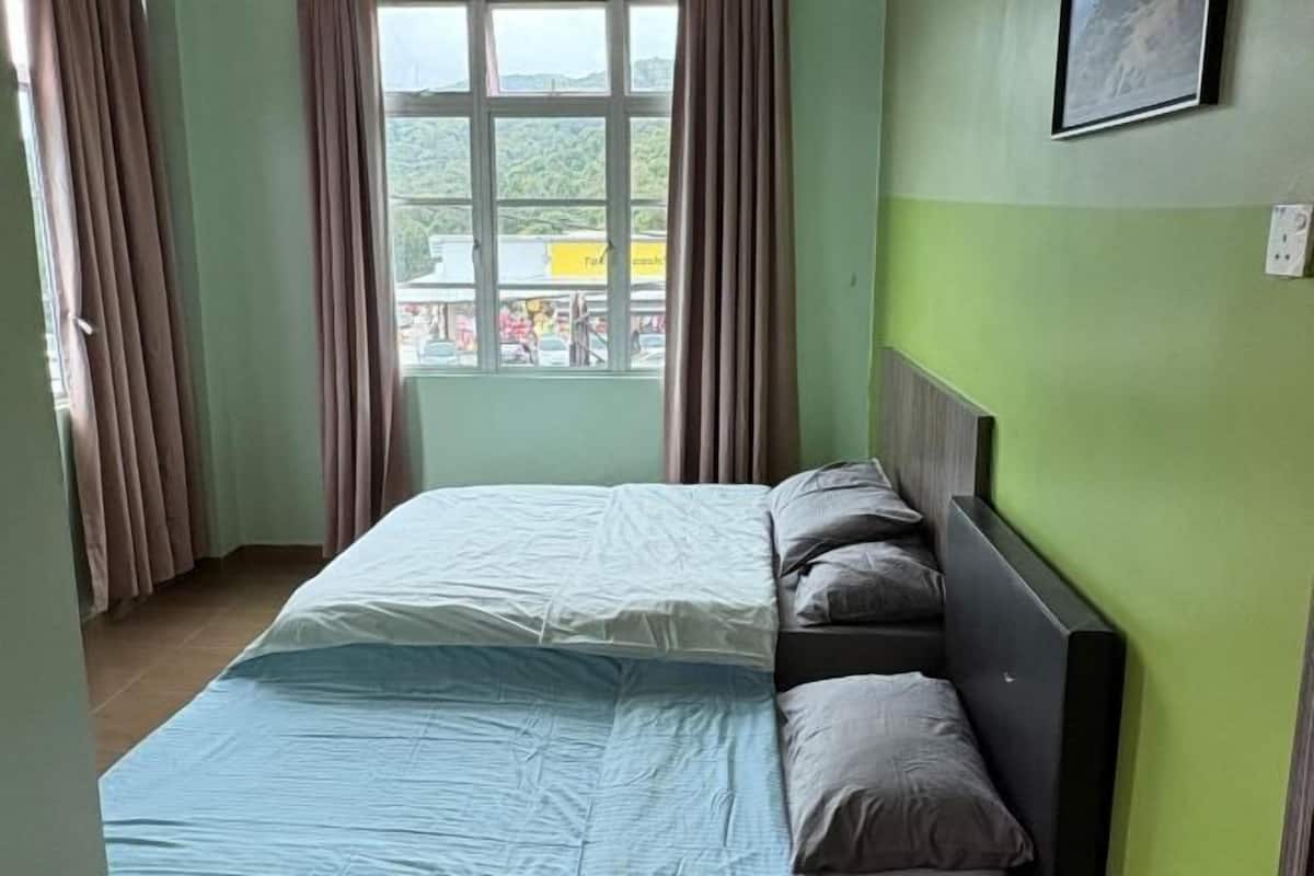Una habitación con cama, cortinas, ventana y pared verde.