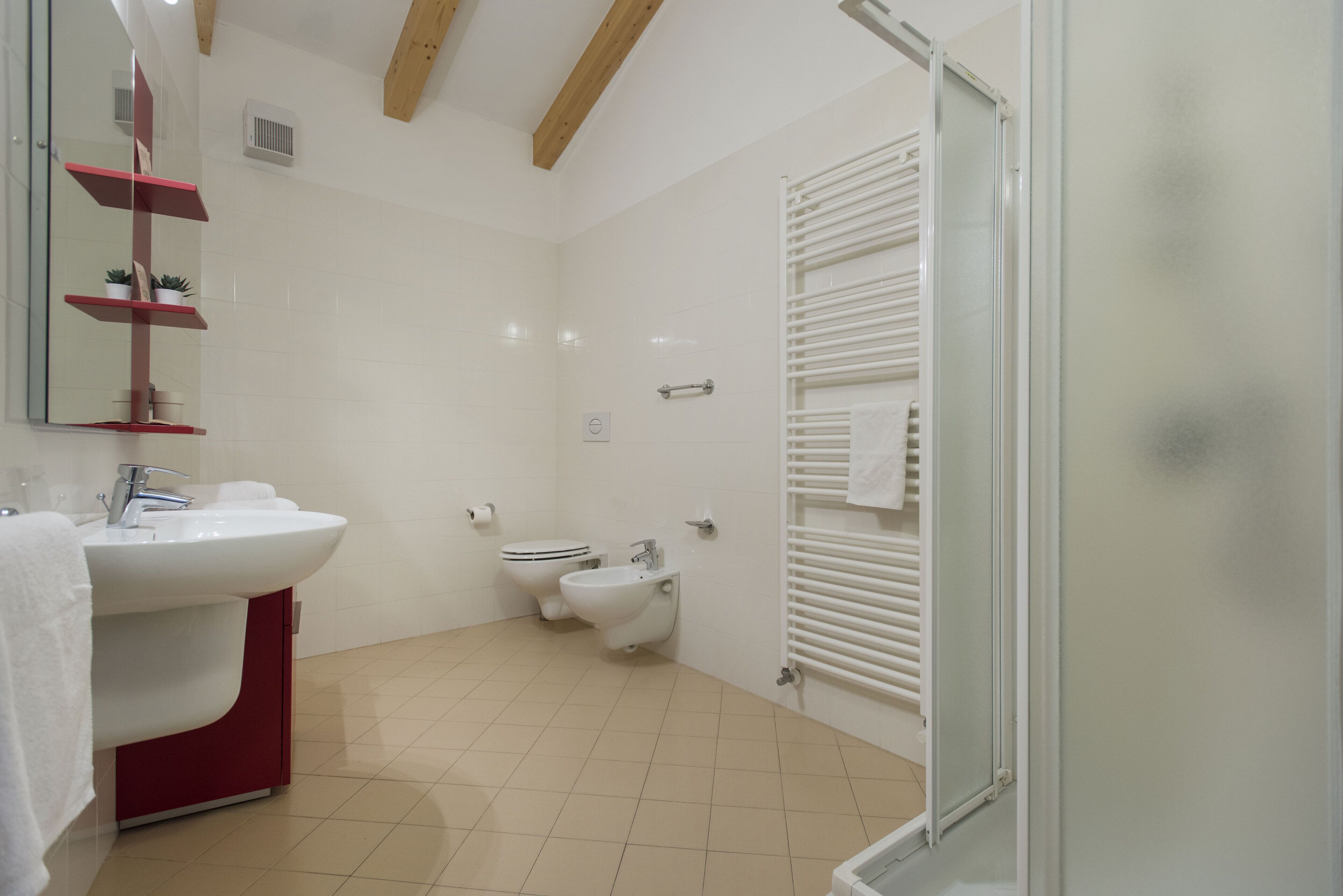 Une salle de bain moderne avec un lavabo blanc, des toilettes, un bidet et une douche à parois de verre.
