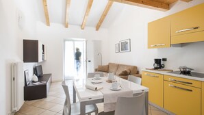 Een moderne keuken met gele kastjes, een eettafel met stoelen en een houten plafond.