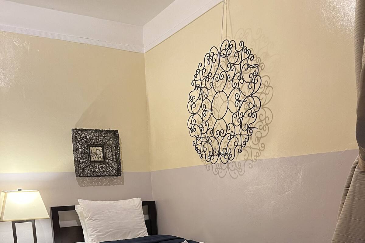 A neatly arranged bedroom with a bed, bedside table, lamp, and decorative wall art.