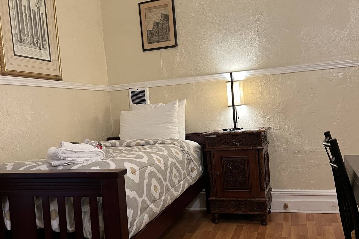 A bedroom with a wooden bed, a nightstand, a lamp, and two framed pictures on the wall.