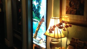 A room with a clock, a framed picture, a lamp, and a potted plant. - Luz Hotel (San Francisco)