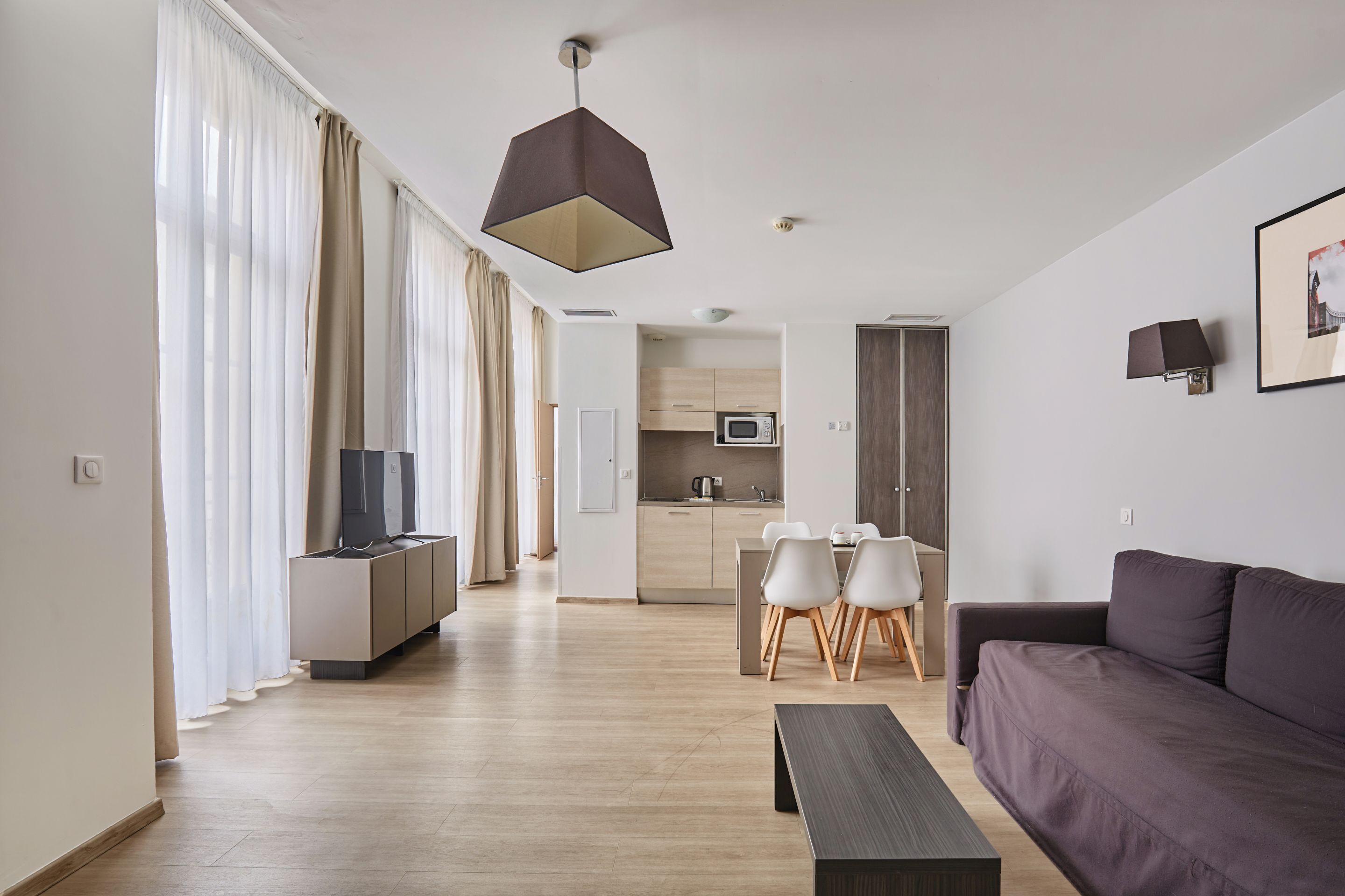 Een modern appartement met een woonruimte, eethoek en keuken.