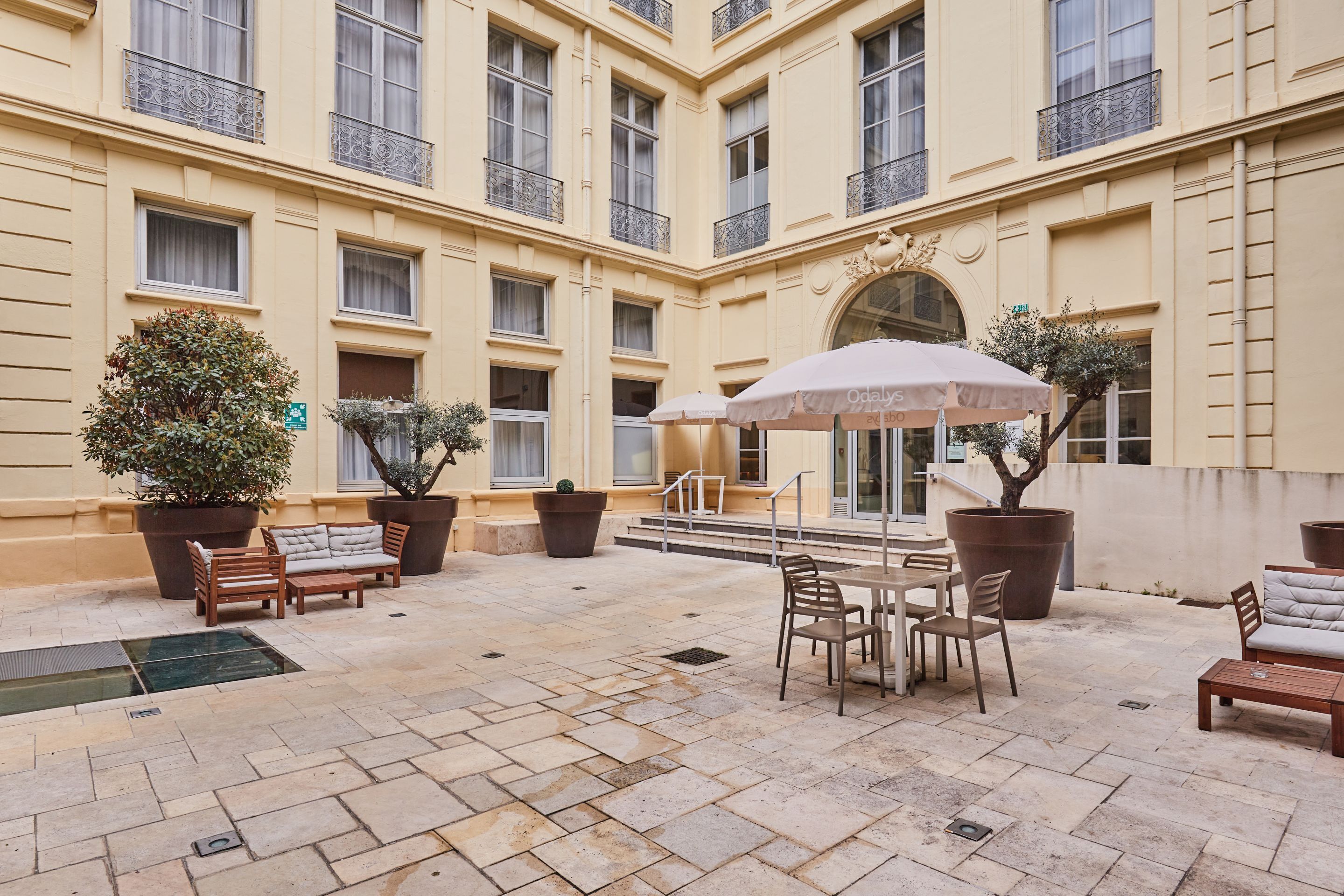 Un patio con mobiliario exterior, plantas en macetas y un ventanal grande.