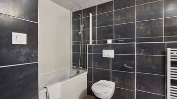 Une salle de bain moderne équipée d’une baignoire, de toilettes et d’un espace douche.