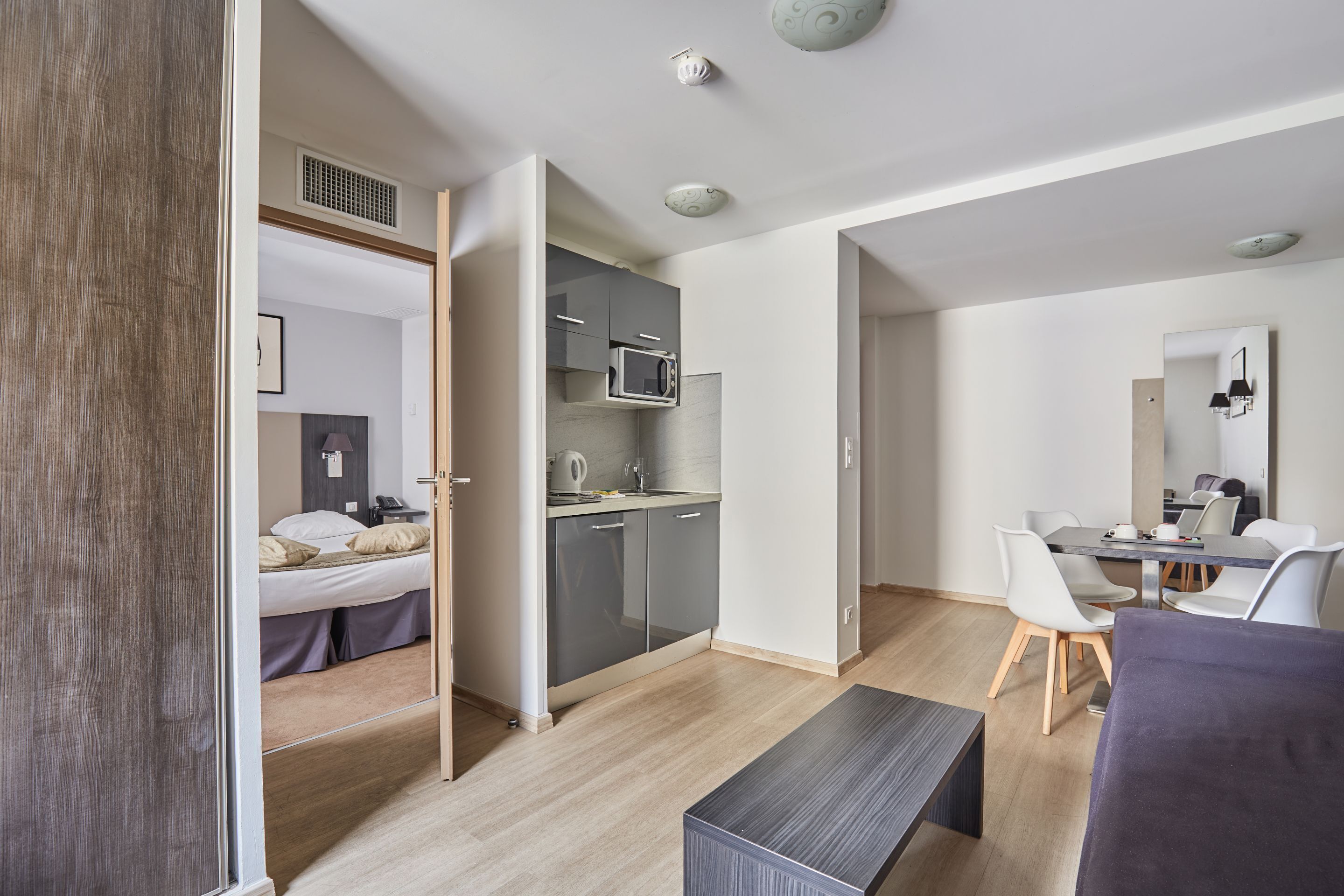 Une chambre d’hôtel moderne équipée d’un lit, d’une kitchenette, d’un coin repas et d’une salle de bain.