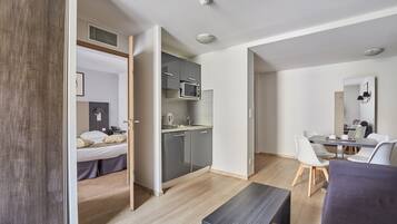 Una habitación de hotel moderna con cama, kitchenette, zona de comedor y baño.