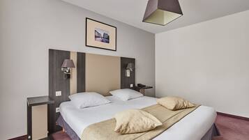 Quarto de hotel moderno com uma cama grande, mesas de cabeceira, uma luminária de parede e um quadro emoldurado na parede.