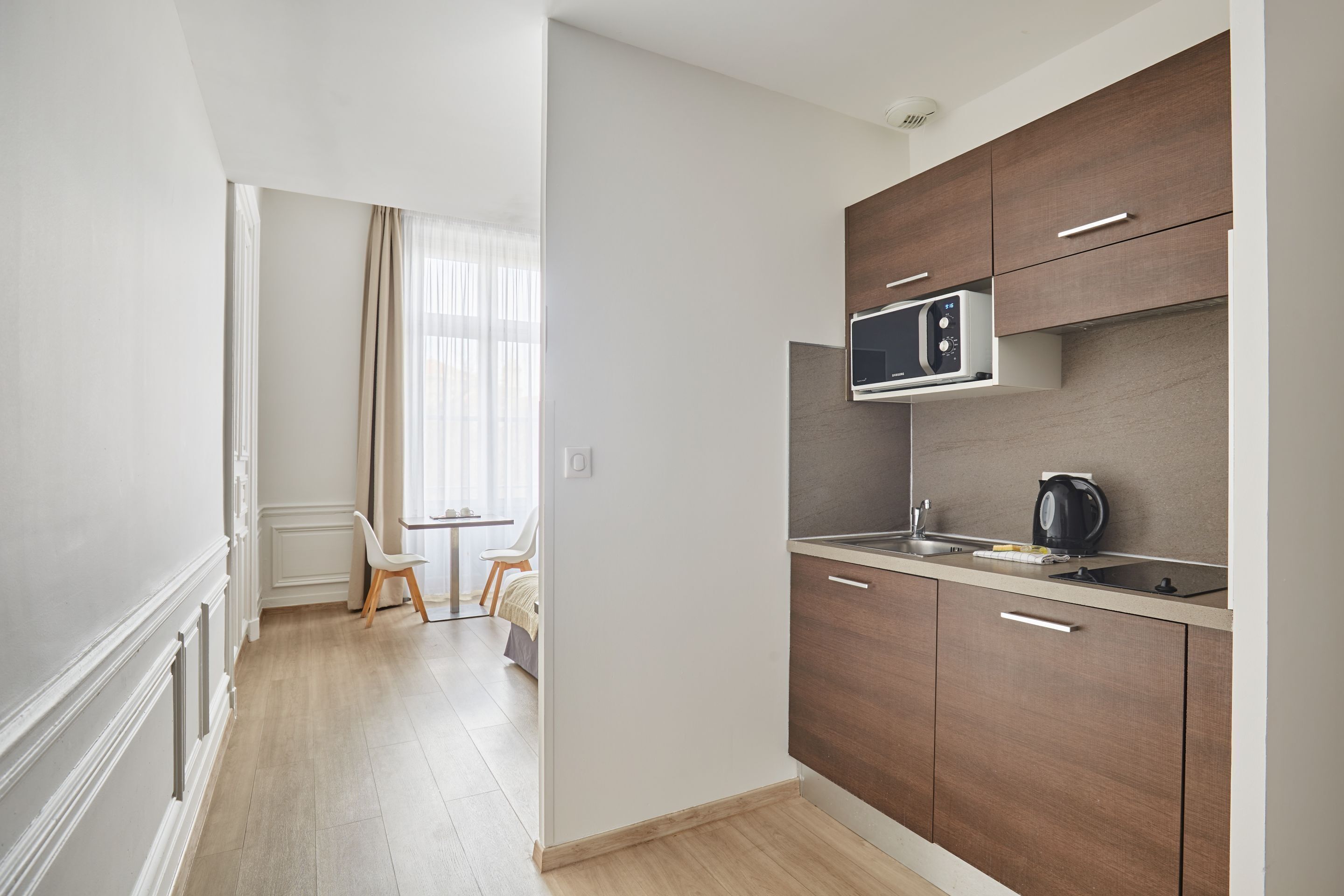 Una cocina moderna con armarios de madera, un microondas y una tetera sobre la encimera.