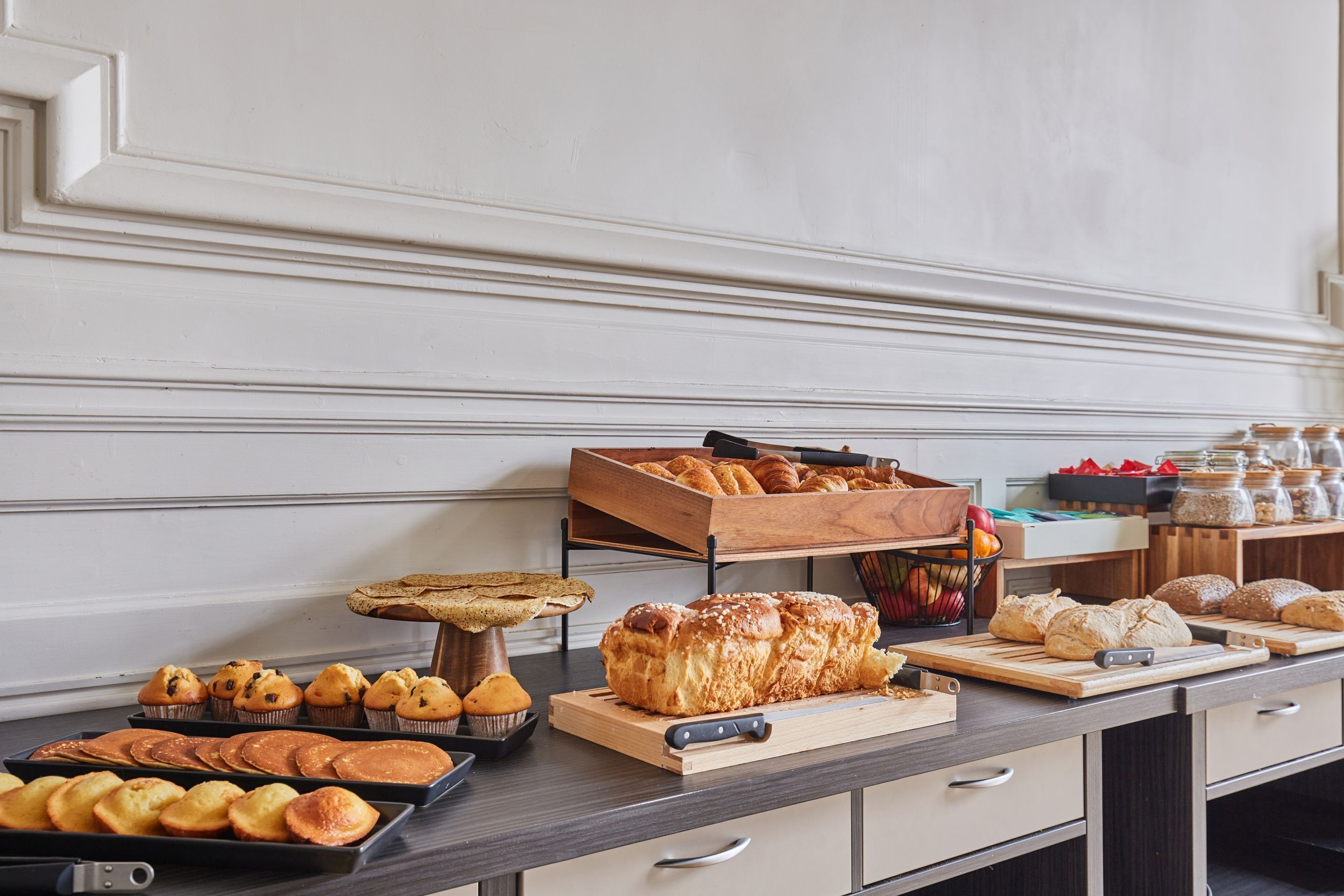 Une table de buffet proposant diverses viennoiseries, notamment des muffins, des pâtisseries et du pain.
