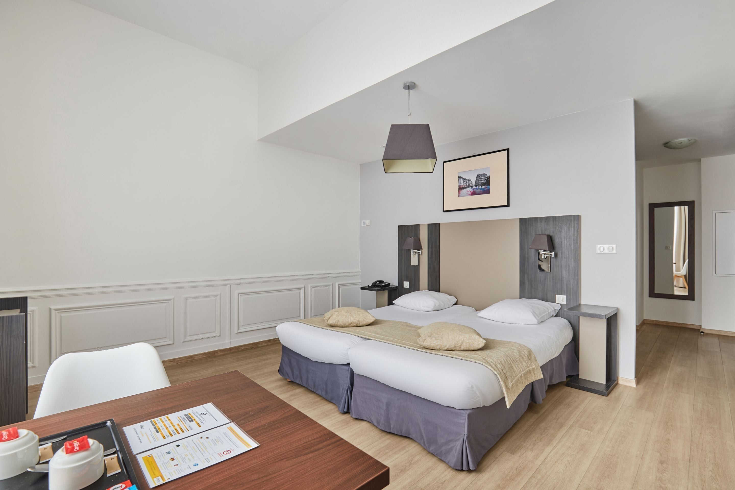 A modern hotel room with a large bed, a desk, and a dining table.