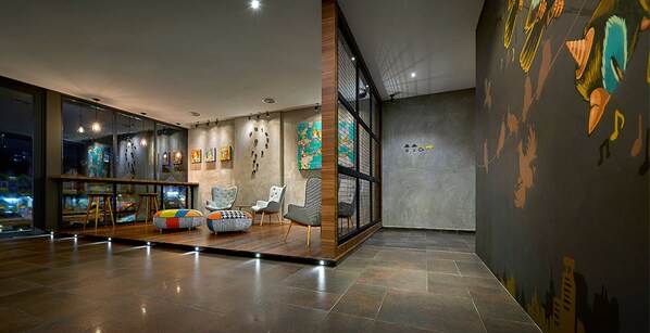 A modern lobby with a seating area, artwork on the walls, and a large window.