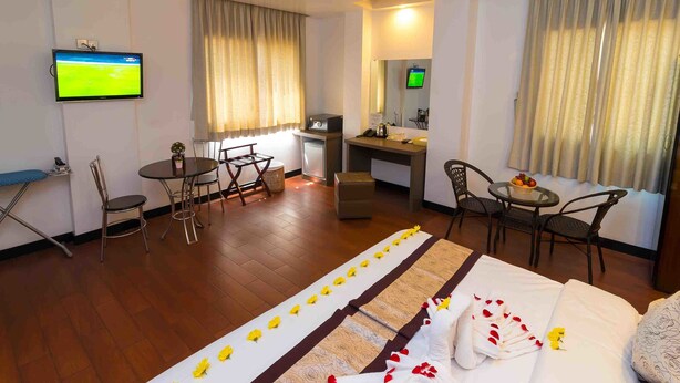 Una habitación de hotel con cama, escritorio, televisor y zona de comedor.
