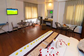 A hotel room with a bed, a desk, a television, and a dining area. - High Five Hotel (Yangon)