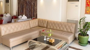Una sala de estar moderna con un sofá seccional color beige, una mesa de centro de vidrio y un área de comedor con una mesa dispuesta para dos.