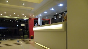 Un vestíbulo moderno con una recepción, un reloj y una planta en maceta.