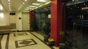Un vestíbulo con pared roja, puerta de cristal, un sofá y plantas en macetas.