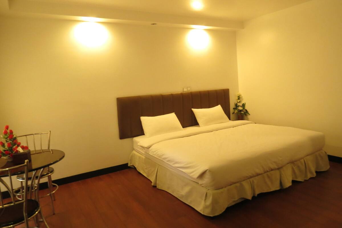 Ein Hotelzimmer mit einem Bett, einem kleinen Tisch mit Stühlen und einer Vase mit Blumen.