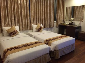 Two single beds with matching headboards, a small desk with a mirror, and a wooden bench. - High Five Hotel (Yangon)