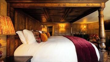 A large bed with a wooden headboard, a red throw blanket, and multiple pillows.