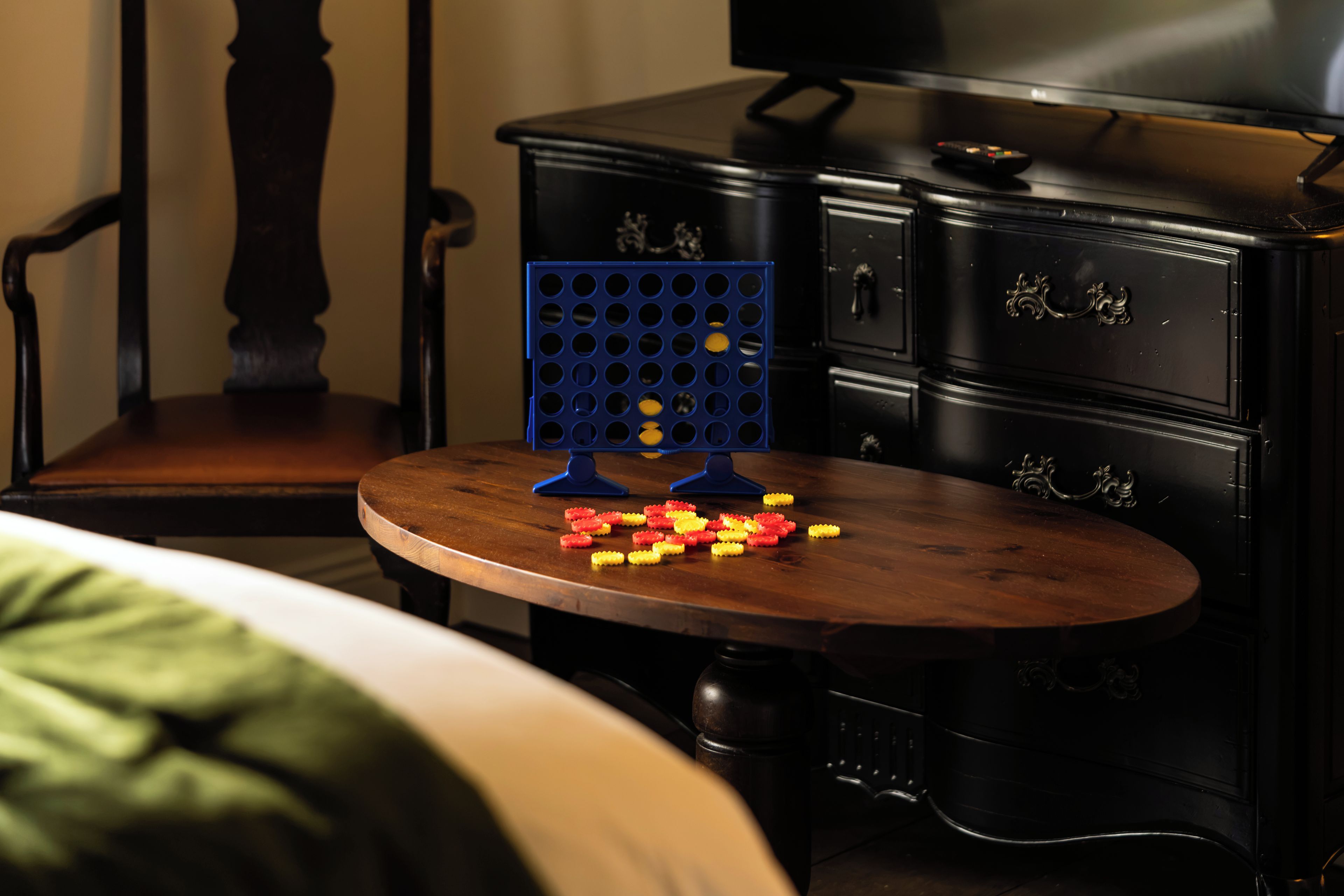 A room with a wooden table, a blue pegboard, and a black dresser.