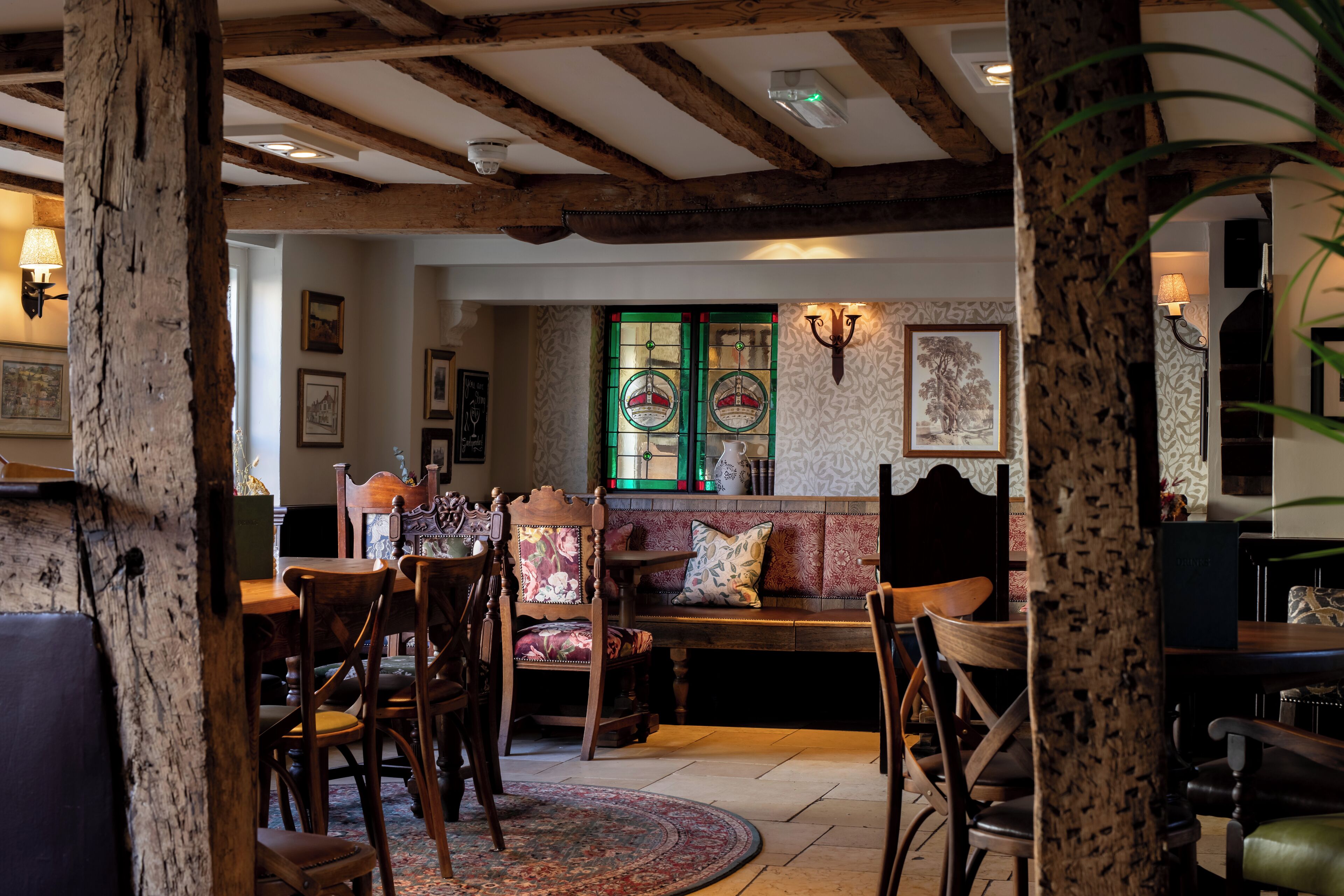 A cozy room with wooden beams, a bench, and chairs.