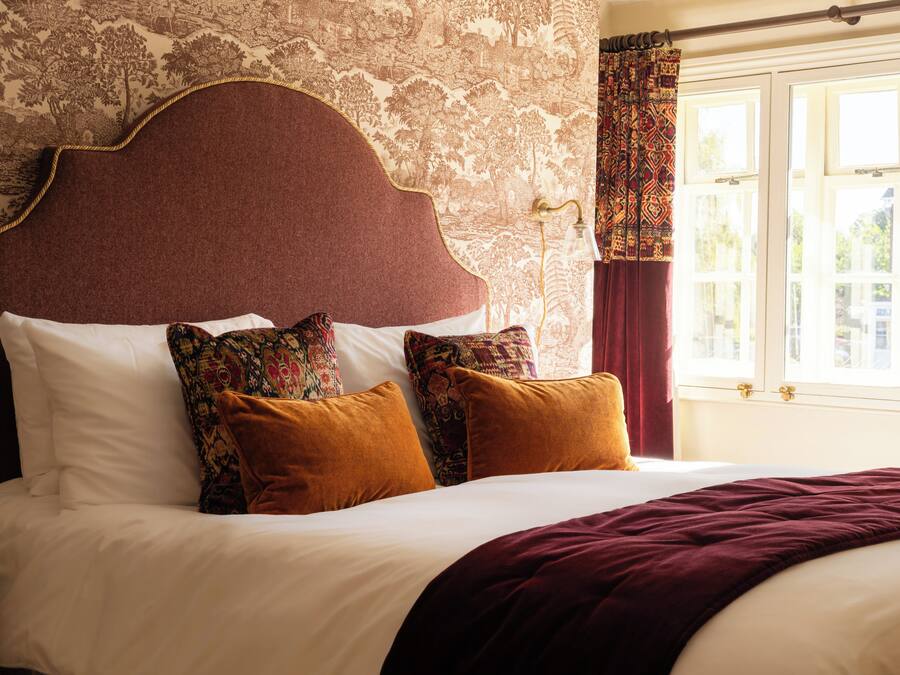 A bed with a headboard, multiple pillows, and a blanket.