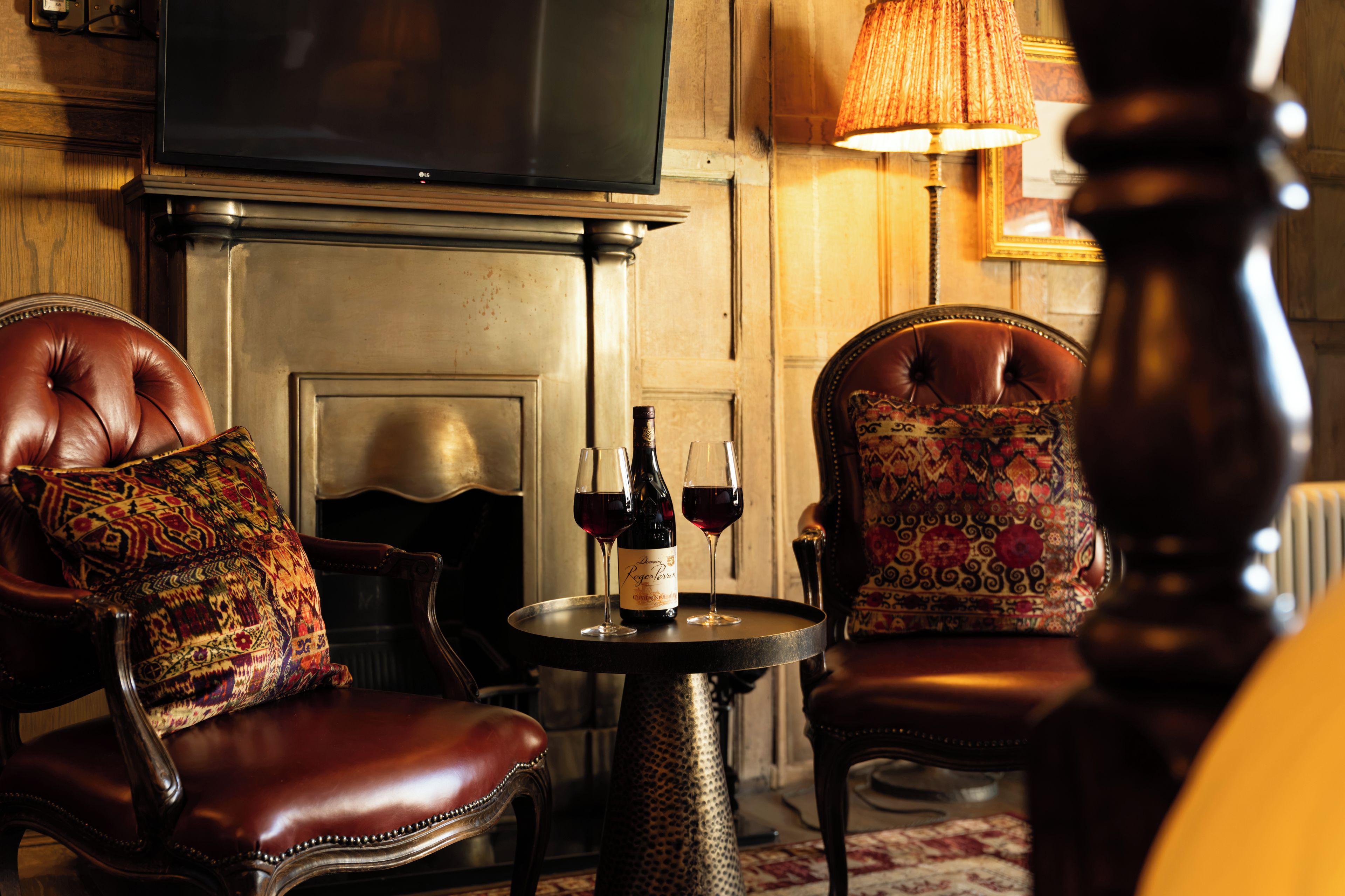 A cozy room with leather armchairs, a fireplace, and a television.