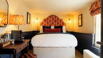 Una habitación de hotel con una cama, mesitas de noche, un escritorio y un radiador.