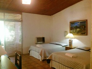 Ein Schlafzimmer mit zwei Betten, einem Fernseher, einer Lampe und einem Bild an der Wand.