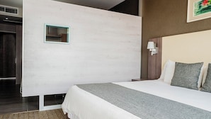 A modern hotel room with a large bed, a small window, and a wall-mounted light fixture. - Hotel Casa Inn Galerias (Celaya)