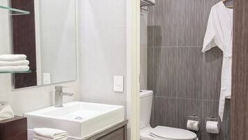 Un baño moderno con lavamanos, espejo y retrete blancos.