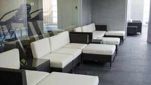 A row of wicker sofas with white cushions in a modern indoor setting. - Hotel Casa Inn Galerias (Celaya)