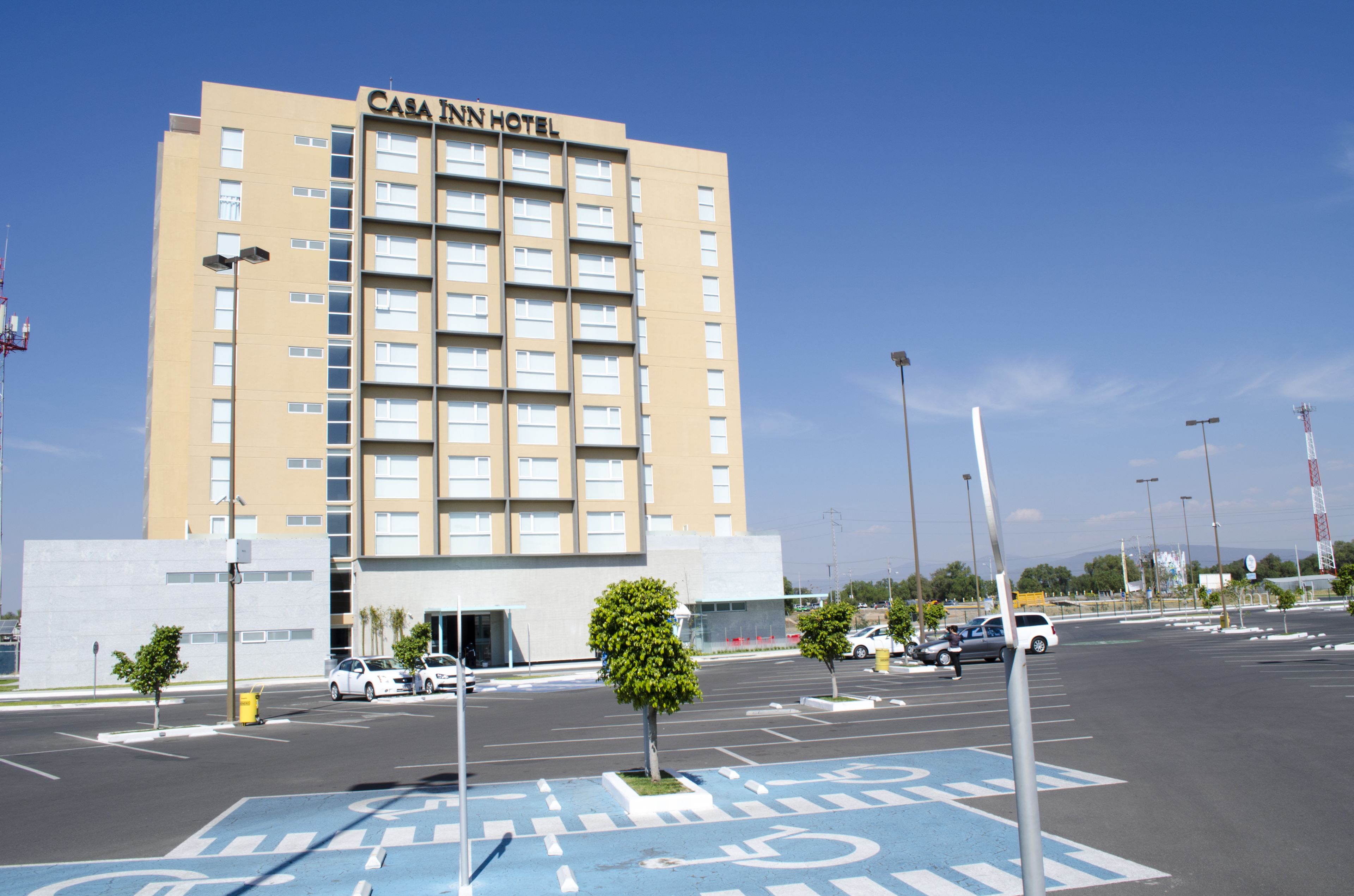 A multi-story hotel with a modern design, featuring a prominent entrance and a parking lot with marked handicapped spaces.