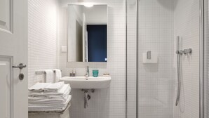 A bathroom with a white sink, a mirror, and a shower.