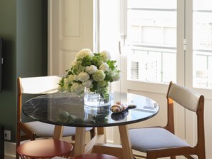 A round glass table with a vase of white flowers, two wooden chairs, and a view of a building through a window. - Flattered to be in Tomar (Tomar)