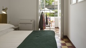 A bedroom with a bed, a desk, and a window.