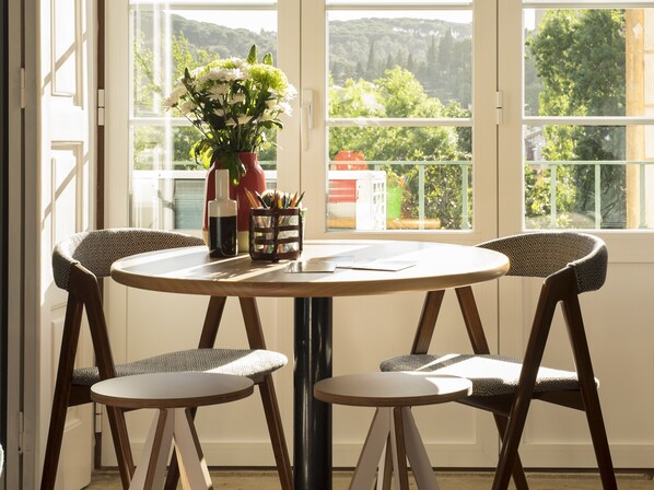 A round table with four chairs, a vase with flowers, and a pen holder with pencils.