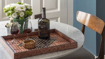 Una mesa con una botella de vino tinto Tawny Porto, dos copas de vino tinto, un florero con flores blancas y una bandeja decorativa.