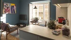 Une cuisine moderne dotée d’un grand îlot central, un coin repas avec une table ronde et un salon avec un canapé et un téléviseur.