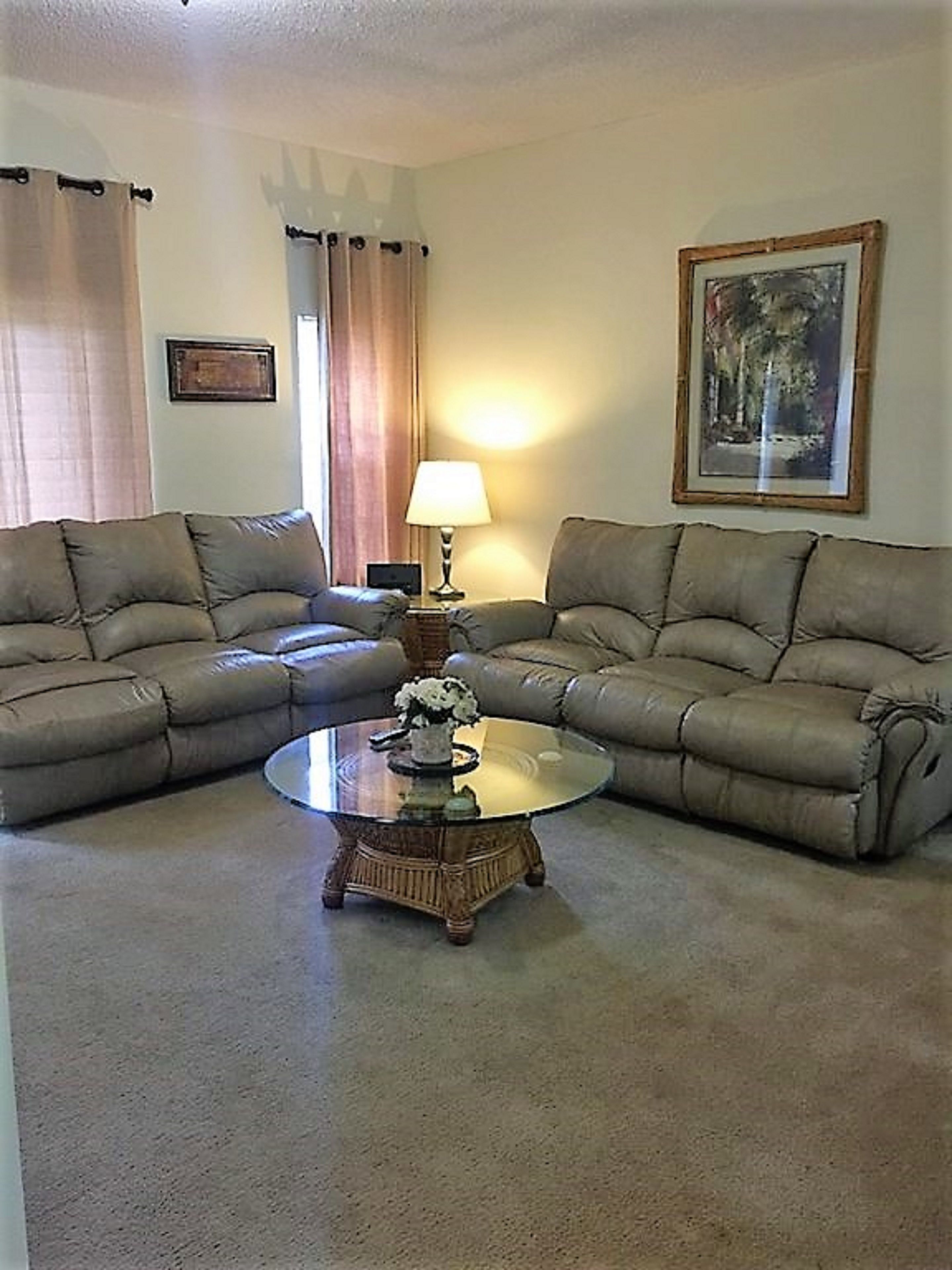 A living room with two sofas, a coffee table, a lamp, and a painting on the wall.