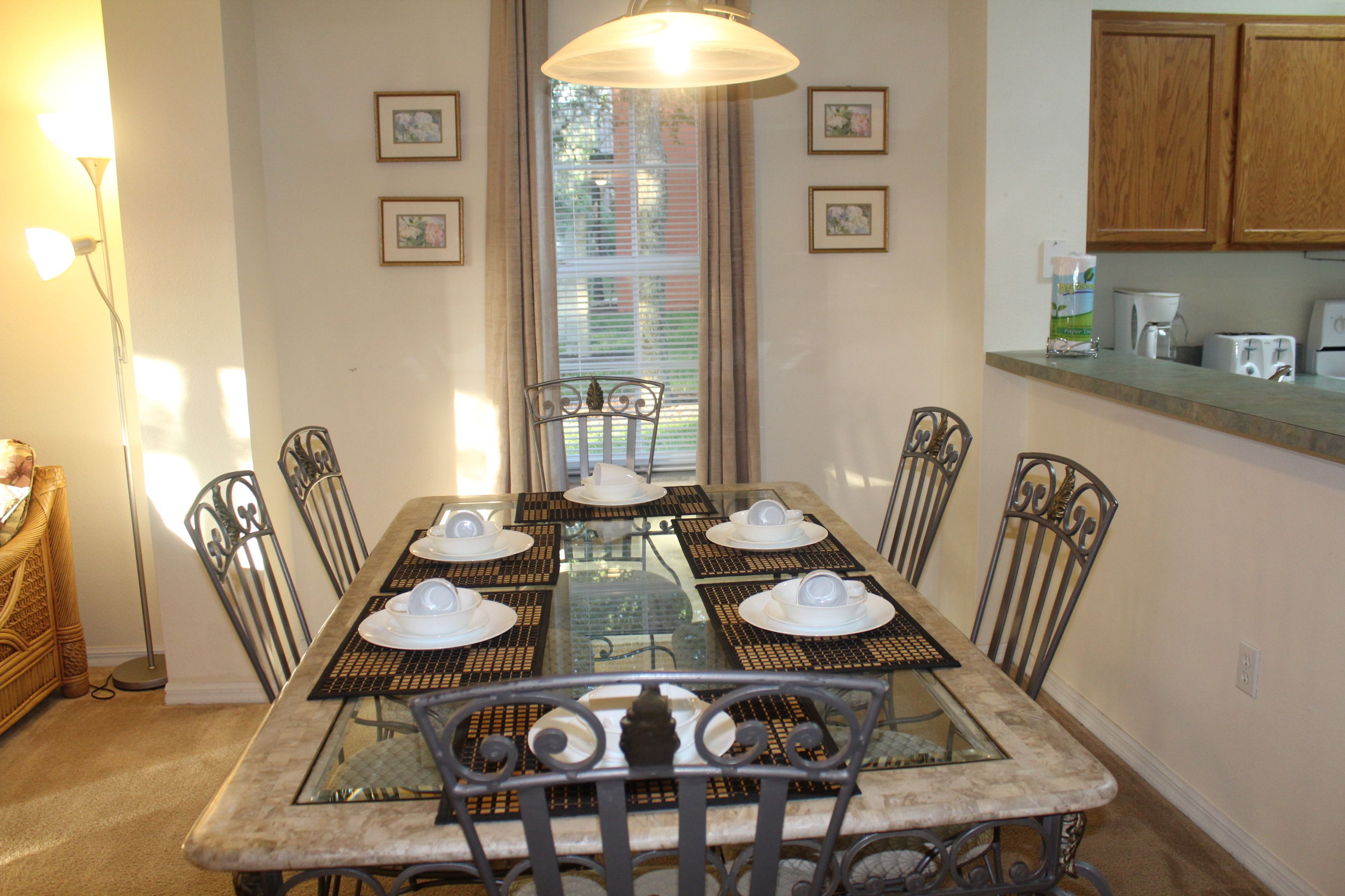 A dining area with a glass-top table, metal chairs, and a chandelier.