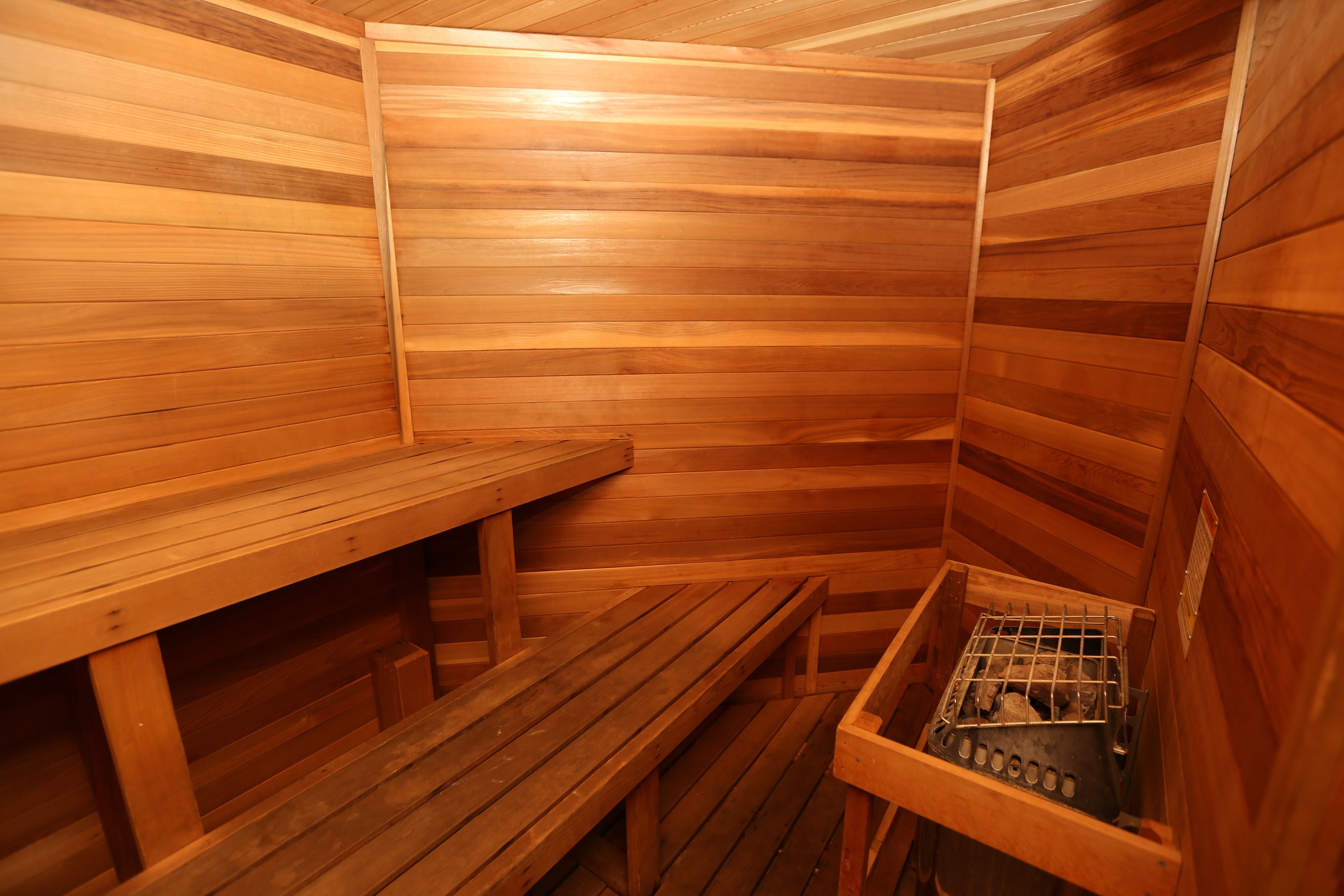 A sauna with wooden benches and a metal container for ashes.