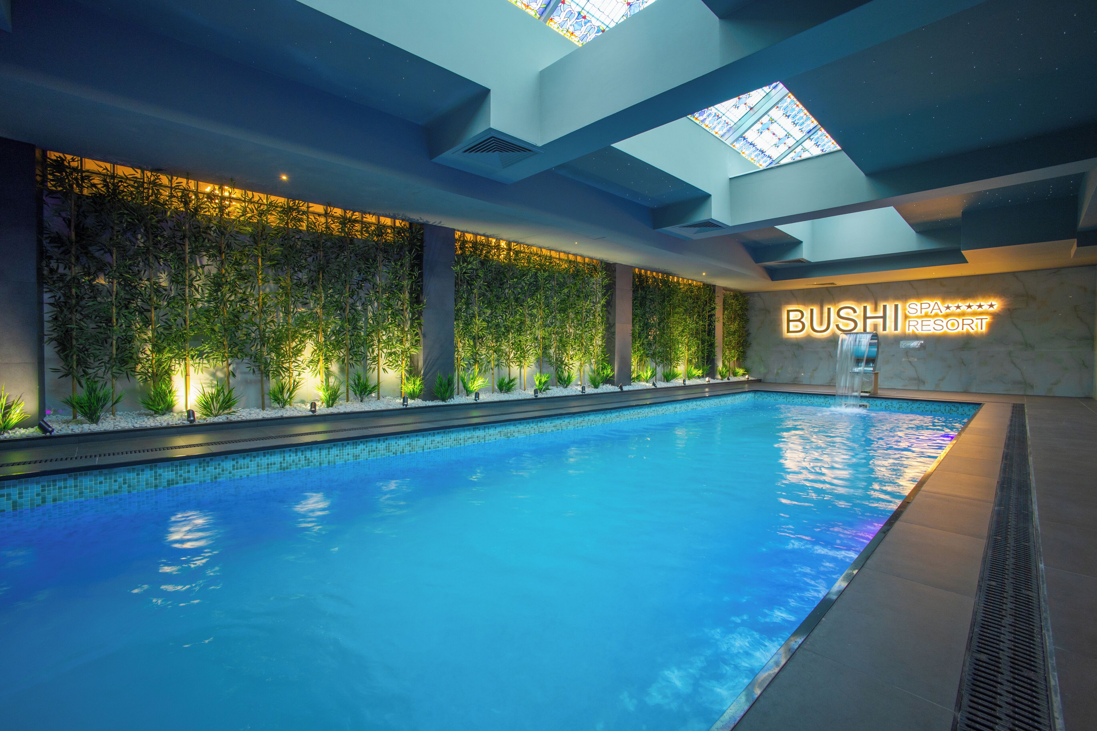 Ein Swimmingpool mit einer Grünwand und einem Schild mit der Aufschrift 'BUSHI RESORT'.