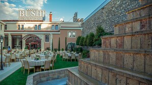 A resort with outdoor dining, a pool, and a stone wall. - Bushi Resort & Spa (Skopje)