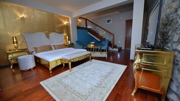 Un dormitorio con una cama grande, una pared decorada en dorado, una escalera y una silla azul.