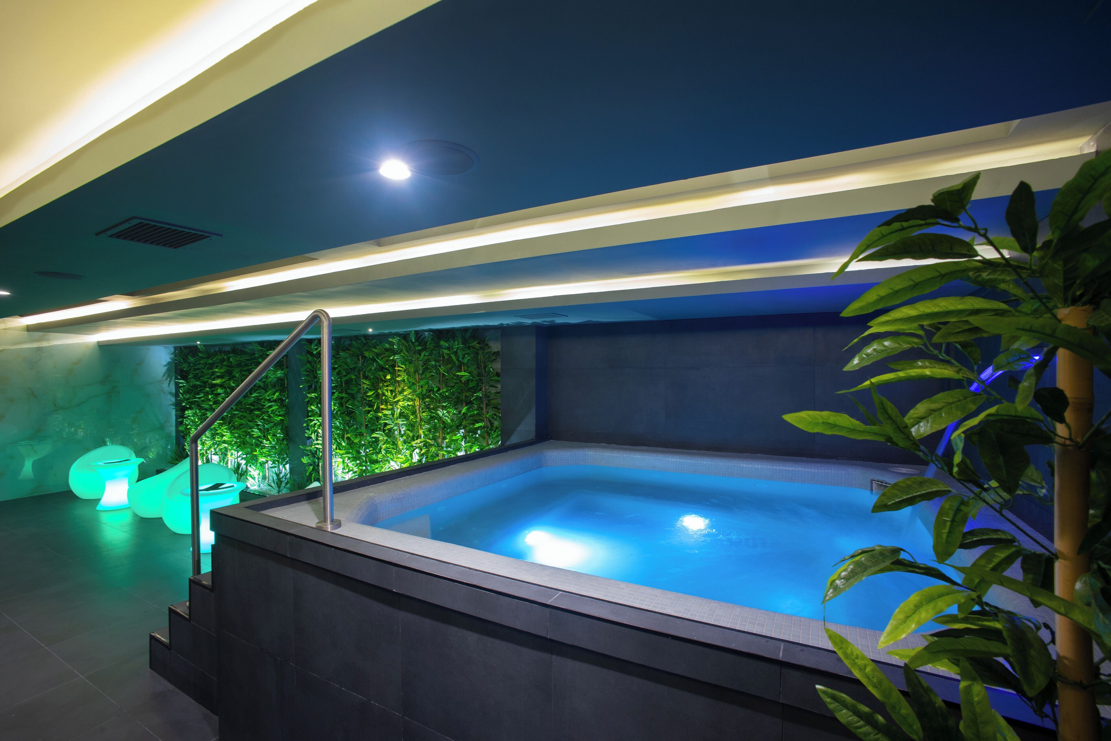 Ein moderner, überdachter Pool mit freier Sicht auf das Wasser, eine Treppe, die zum Pool führt, und eine Topfpflanze auf der rechten Seite.
