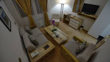 A compact living space with a sofa, a coffee table, a desk, a chair, a TV, and a lamp.