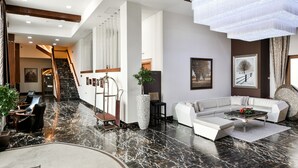 A spacious living area with a marble floor, a white sofa, a coffee table, and a staircase leading to another room. - Bushi Resort & Spa (Skopje)