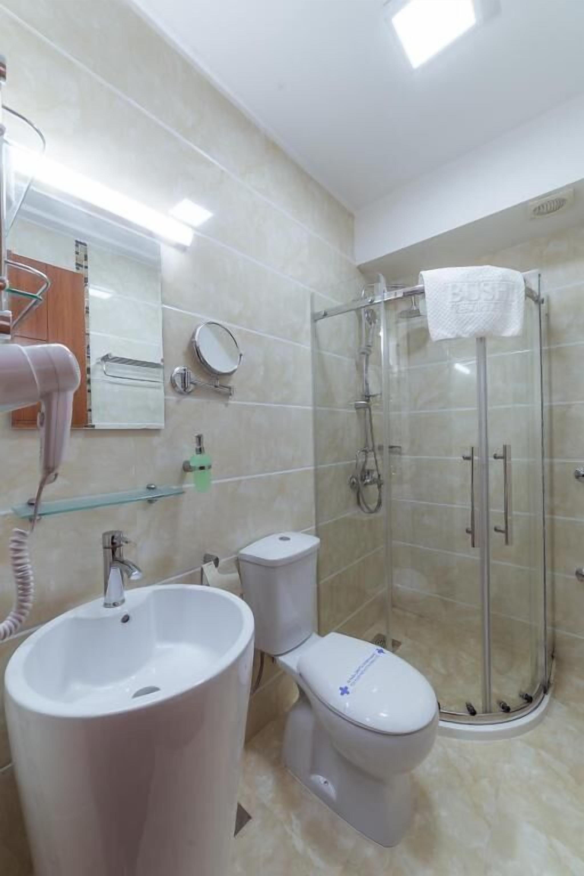 A bathroom with a glass-enclosed shower, a sink, and a toilet.
